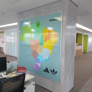quadro com o mapa do brasil com estados coloridos e municípios, fundo azul acinzentado em uma parede cinza do escritório da adidas